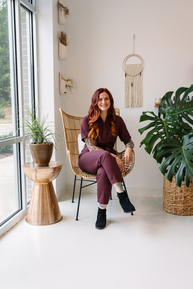 a person sitting on a wicker chair in front of potted plants