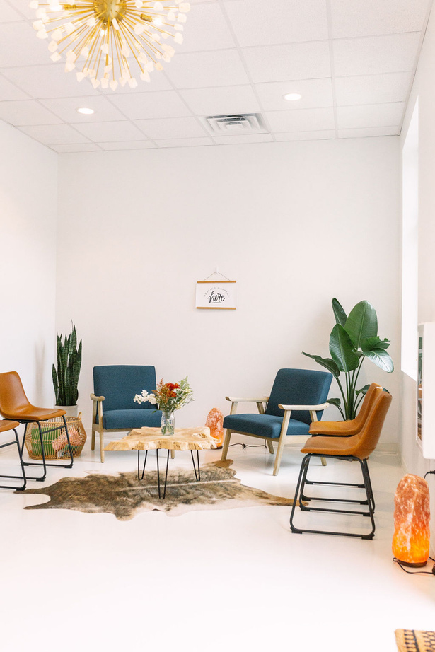 a white room with blue chairs and a chandelier
